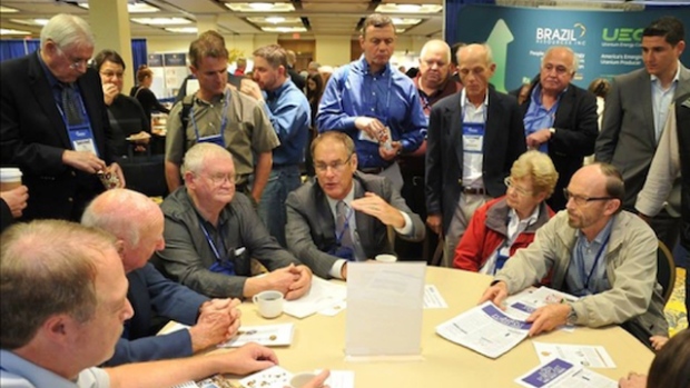 Attendees gather around a Speaker Table to chat with Rick Rule. 
