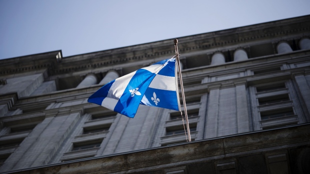A Quebec flag flies outside the Sun Life building in Montreal, Quebec, Canada, on Monday, Aug. 20, 2018. Median single-family home prices in Montreal rose 5.7% to C$336,250 in July from a year ago, according to the Greater Montreal Real Estate Board (GMREB). 