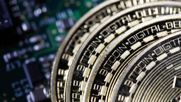 Three coins representing Bitcoin cryptocurrency sit on a computer circuit board in this arranged photograph in London, U.K. 