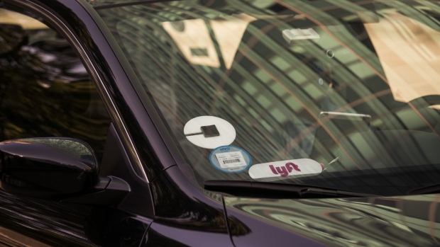 Lyft Inc. and Uber Technologies Inc. logos are seen on the windshield of a vehicle in New York, U.S., on Thursday, Aug. 9, 2018. New York's city council dealt a political blow to Uber Technologies Inc. and other app-based car-for-hire companies by approving a one-year industry wide cap on new licenses and giving the city Taxi & Limousine Commission authority to set minimum pay standards for drivers. 