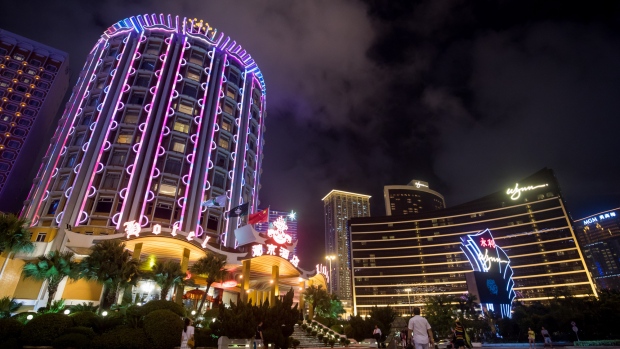The Casino Lisboa, operated by SJM Holdings Ltd., left, and Wynn Resorts Ltd.'s Wynn Macau casino resort stand illuminated at night in Macau, China, on Tuesday, July 24, 2018. Earnings from Macau casino operators are expected to remain healthy for the second quarter, though concerns are increasing over a slowing China economy and a weaker showing by high-stakes gamblers. Photographer: Paul Yeung/Bloomberg