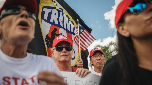 A demonstrator holds an American flag during a protest outside the Broward County Supervisor of Elections office in Lauderhill, Florida, U.S., on Monday, Nov. 12, 2018. Florida's Senate and governor's races have gone to a recount that will decide two key offices in the largest U.S. swing state, setting off outcries from Republicans led by President Donald Trump and Rick Scott, the state's governor now vying to be a U.S. Senator. Photographer: Jayme Gershen/Bloomberg