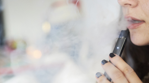 A person smokes a Juul Labs Inc. e-cigarette in this arranged photograph taken in the Brooklyn Borough of New York, U.S., on Sunday July 8, 2018. 