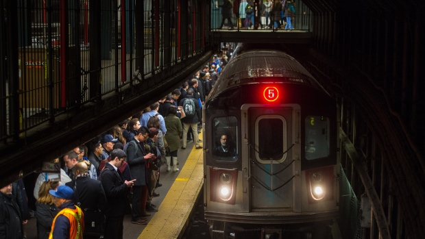 Commuters wait to board a 5 train to arrive at the 14th Street-Union Square subway station in New York, U.S., on Thursday, March 26, 2015. It now costs $2.75 to ride the New York subway as of March 22, a 25-cent increase that will help fund the Metropolitan Transportation Authority's budget. 