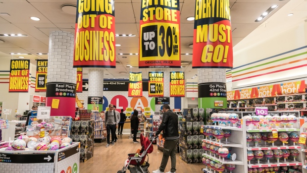 Customers pass in front of "Going Out Of Business"signs hanging on display at a Toys 'R' Us retail store at Times Square in New York, U.S. 