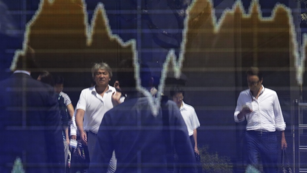 Pedestrians are reflected in an electronic stock board outside a securities firm in Tokyo, Japan, on Thursday, Aug. 30, 2018. Japan's Topix index closed lower after fluctuating as investors assessed trade frictions and geopolitical risks. 