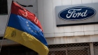 A Venezuelan flag flies in front of Ford Motor Co. signage in Caracas, Venezuela, on Wednesday, April 26, 2017. Foreign companies operating in Venezuela have been beset by disruptions stemming from goods shortages, strikes and police raids. 