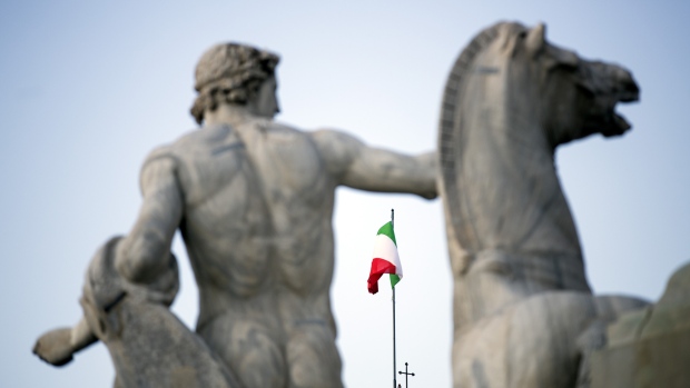 The Italian national flag, seen between statues, flies atop the Quirinale palace, the office of Italy's president in Rome, Italy. 