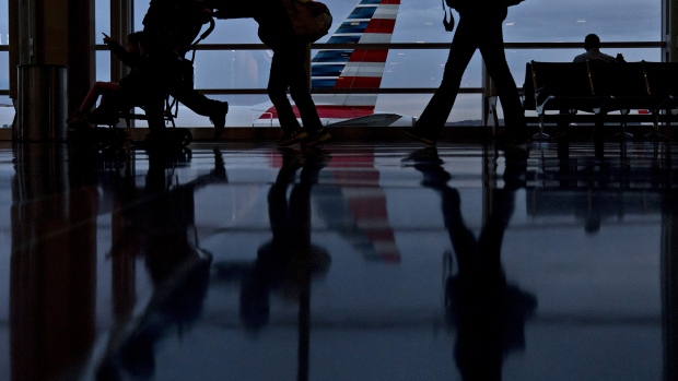 Travelers walk past an American Airlines Group Inc. aircraft at Ronald Reagan National Airport (DCA) in Washington, D.C. 