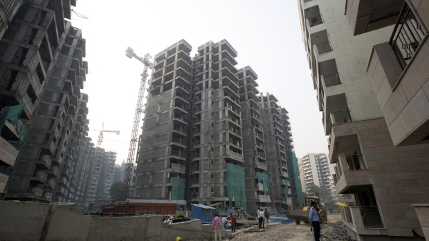 Workers labor in a construction site at the East Kidwai Nagar General Pool Residential Accommodation (GPRA) Redevelopment Project, redeveloped by National Buildings Construction Corp. (NBCC), stands in the background in Delhi, India, on Wednesday, Oct. 24, 2018. The district, one of Delhi's flagship smart city projects developed for an enclave of civil servants, shows some of the obstacles that can make urban regeneration a slow and painful process in India. The project, begun in 2014, will replace 2,444 old low-rise homes with 4,608 apartments in modern 14-story towers, together with car parking and retail space. Scheduled to be completed by June, the 87-acre project is touted as a poster child for new government housing, with solar panels, on-site waste management and rainwater harvesting. 