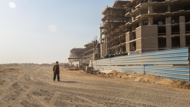 A worker walks past the complex of ministerial buildings under construction at the site of the new Cairo Administrative Capital near Cairo, Egypt, on Tuesday, Feb. 20, 2018. The multiphase project envisages transforming a 700-square-kilometer swath of desert into a hub for Parliament, government ministries, foreign embassies, and major companies, easing pressure on traffic-choked Cairo. 