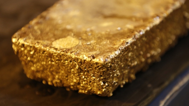A large unrefined gold bar sits on a workbench during processing . 