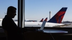 A traveler works on a laptop computer as Delta Air Lines Inc. planes are seen outside a window at Salt Lake City International airport (SLC) in Salt Lake City, Utah, U.S., on Friday, July 6, 2018. Delta Air Lines Inc. is scheduled to release earnings figures on July 12. 