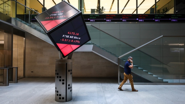 An employee walks past FTSE All share price information displayed on an illuminated rotating cube in the atrium of the London Stock Exchange Group Plc's offices in London, U.K., on Friday, July 6, 2018. U.K. Prime Minister Theresa May is about to unveil in more detail than ever the kind of divorce from the EU she thinks the country, Parliament and Brussels will accept, with a policy document called a "white paper." 