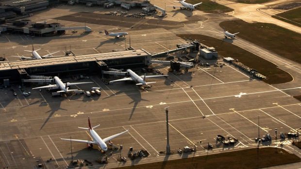 Aircrafts taxi along the perimeter of the north runway, center, and past passenger terminal buildings at London Heathrow Airport. 