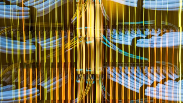 Light trails from network switches illuminate fiber optic cables, center, and copper Ethernet cables inside a communications room at an office in London, U.K., on Monday, May 21, 2018. The Department of Culture, Media and Sport will work with the Home Office to publish a white paper later this year setting out legislation, according to a statement, which will also seek to force tech giants to reveal how they target abusive and illegal online material posted by users. 