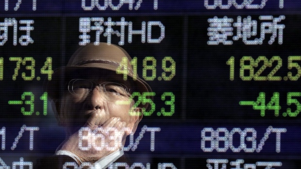A pedestrian is reflected in an electronic stock board outside a securities firm in Tokyo. 