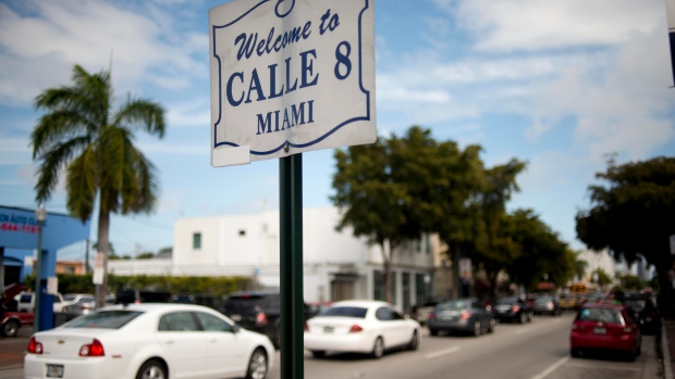 Cars pass by a sign welcoming people to Calle 8, or Eighth Street, Miami