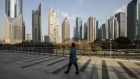 A pedestrian walks on an elevated walkway past buildings in Pudong's Lujiazui Financial District in Shanghai, China, on Friday, Dec. 28, 2018. China announced plans to rein in the expansion of lending by the nation's regional banks to areas beyond their home bases, the latest step policy makers have taken to defend against financial risk in the world's second-biggest economy. Photographer: Qilai Shen/Bloomberg