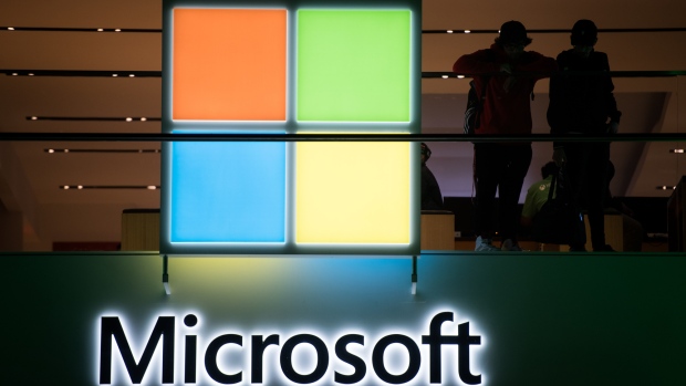 Customers stand near the Microsoft Corp. logo during the Microsoft Corp. Xbox One X game console global launch event in New York, U.S., on Monday, Nov. 6, 2017. As Microsoft Corp. begins selling a new Xbox console, the focus of its video-game unit is shifting toward software and services. The company plans to increase investment in developing in-house video games. 
