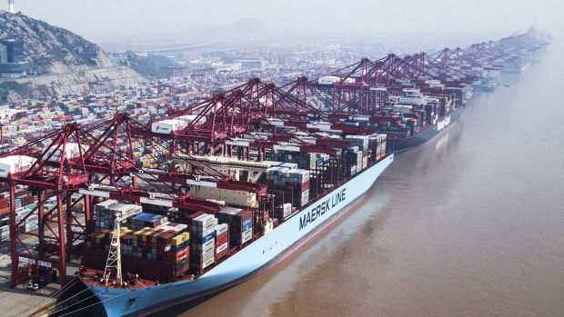An A.P. Moller-Maersk A/S container ship and a Hapag-Lloyd AG container ship are docked as shipping containers stand in a terminal at the Yangshan Deep Water Port in this aerial photograph taken in Shanghai, China, on Friday, March 23, 2018. 