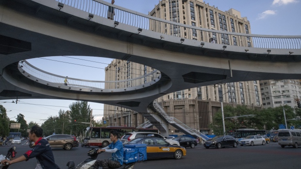 Traffic moves through an intersection under a pedestrian overpass as a building stands in the background in Beijing, China, on Thursday, July 26, 2018. Beijing residents have been breathing some of the cleanest air in a decade as they begin to reap the benefits of China's anti-smog push. 