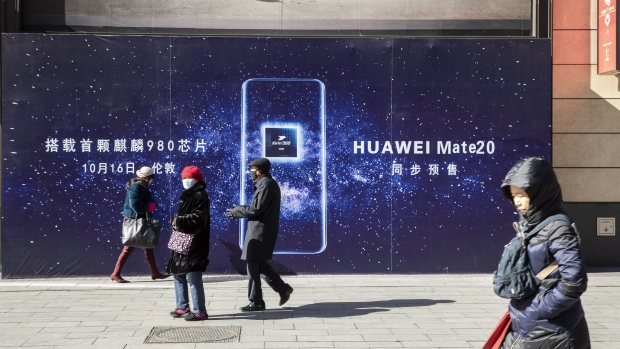 Pedestrians walk past an advertisement for the Huawei Technologies Co. Mate 20 smartphone in Beijing