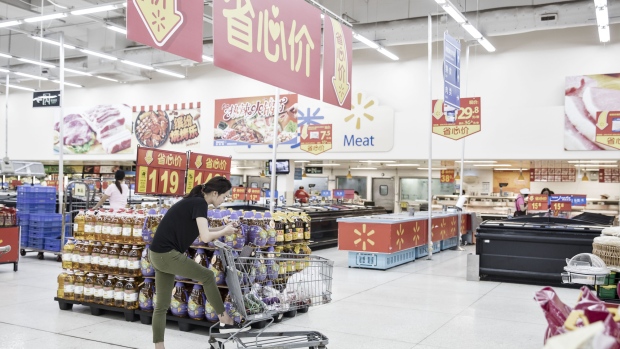 An employee completing an online customer order holds a scanning device as she wheels a shopping cart through a Walmart Stores Inc. outlet in Shenzhen, China, on Tuesday, Oct. 18, 2016. Walmart sees big potential in China: Its Sam's Club in Shenzhen, a fast-growing urban center in the southeast, is the chain’s best-performing outlet globally. Photographer: Qilai Shen/Bloomberg