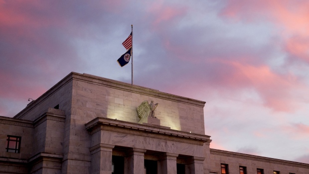 A U.S. flag flies on top of the Marriner S. Eccles Federal Reserve building at sunrise in Washington, D.C. 