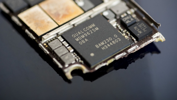A Qualcomm Inc. baseband modem integrated circuit (IC) chip, center, of an Apple Inc. iPhone 6 smartphone is seen in an arranged photograph in Bangkok, Thailand, on Saturday, Feb. 3, 2018. Apple Chief Executive Officer Tim Cook told shareholders on Feb. 13 at the company's annual meeting to expect higher dividends and stressed that succession planning is a priority. 