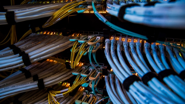 Fiber optic cables, center, and copper Ethernet cables feed into switches inside a communications room at an office in London, U.K., on Monday, May 21, 2018. The Department of Culture, Media and Sport will work with the Home Office to publish a white paper later this year setting out legislation, according to a statement, which will also seek to force tech giants to reveal how they target abusive and illegal online material posted by users. 