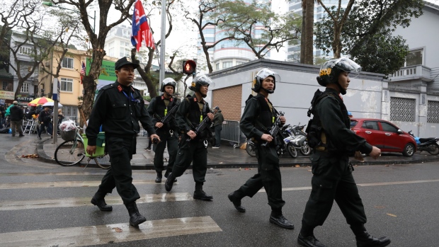 Armed police officers cross a road outside the Melia hotel in Hanoi on Feb. 26. Photographer: SeongJoon Cho/Bloomberg