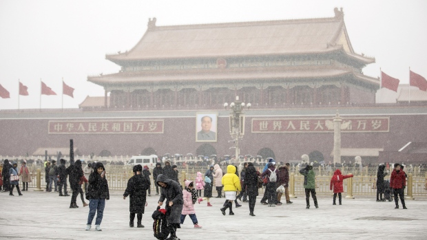 People pose for photographs at Tiananmen Square as snow falls in Beijing, China