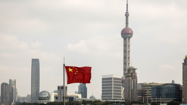 A Chinese national flag flies as skyscrapers of the Pudong Lujiazui Financial District stand across the Huangpu River in Shanghai, China, on Friday, Dec. 28, 2018. China announced plans to rein in the expansion of lending by the nation's regional banks to areas beyond their home bases, the latest step policy makers have taken to defend against financial risk in the world's second-biggest economy. 