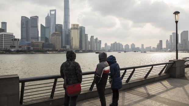 Pedestrians stand along the Bund as skyscrapers of the Pudong Lujiazui Financial District stand across the Huangpu River in Shanghai, China, on Friday, Dec. 28, 2018. China announced plans to rein in the expansion of lending by the nation's regional banks to areas beyond their home bases, the latest step policy makers have taken to defend against financial risk in the world's second-biggest economy. 