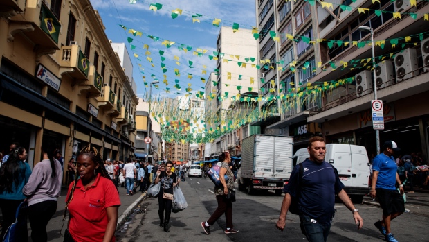 Pedestrians and traffic pass on a street decorated in Brazilian flags ahead of the FIFA World Cup games in downtown Sao Paulo, Brazil, on Wednesday, June 13, 2018. In a curious quirk of Brazil's electoral calendar, for the last 28 years Latin America's largest economy has gone to the polls shortly after the World Cup. In the football-obsessed country, politicians have long attempted to hijack the sport to burnish their image. 