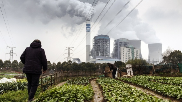 People tend to vegetables growing in a field as emission rises from cooling towers at a coal-fired power station in Tongling, Anhui province, China, on Wednesday, Jan. 16, 2019. China's economy expanded at its weakest pace since 2009, according to figures Monday, with gross domestic product rising 6.4 percent in the fourth quarter from a year earlier. 