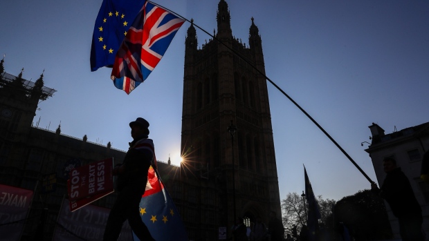 Anti-Brexit campaigners wave a European Union flag and a Union Jack, also known as a Union Flag, during a protest near the Houses of Parliament in London, U.K.,