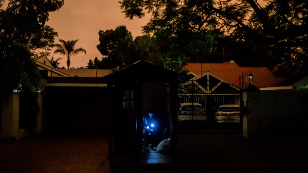 A security guard sits illuminated by light from his mobile phone inside a residential area patrol hut in darkness during a load-shedding power outage period in Pretoria, South Africa, on Wednesday, Feb. 13, 2019. Eskom Holdings SOC Ltd. cut supplies for the fifth day on Thursday and warned its power generation system remains "vulnerable." 