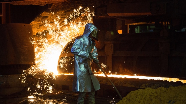 An employee wears protective clothing beside a blast furnace cast house at ThyssenKrupp AG's steel plant in Duisburg, Germany. 