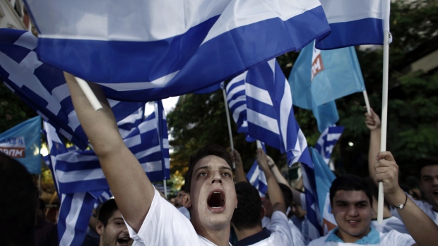 Crowd members shout slogans and wave Greek national flags during a pre-election rally with Evangelos Meimarakis, leader of the New Democracy Party of Greece, not pictured, in Athens, Greece, on Thursday, Sept. 17, 2015. Alexis Tsipras stepped down on Aug. 20 after eight months in power, announcing new parliamentary elections following the political turmoil resulting from his government's signing of a third bailout agreement with Greece's creditors in August. 