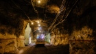 Lights illuminate a mining truck moving through an underground tunnel at a gold mine. 