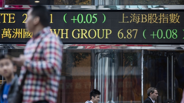 Pedestrians walk past an electronic ticker board displaying stock figures outside the Exchange Square complex, which houses the Hong Kong Stock Exchange, in Hong Kong, China, on Monday, Feb. 11, 2019. The bullish mood building in China’s equity market is entering a new phase, with investors flocking to riskier stocks as trading reopened Monday. 