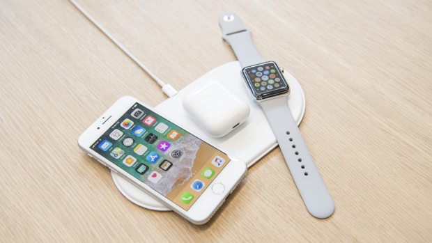 The Apple iPhone 8, Airpods, and Apple Watch sit on the AirPower charger. 