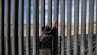 A man looks towards the United States through a fence in Tijuana, Mexico, on Saturday, Nov. 17, 2018. President Donald Trump said Saturday it is a good time to shut down the government to gain leverage with Democrats to fund his demands for a wall along the U.S. border with Mexico. 