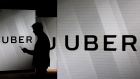 A man checks his smartphone whilst standing amongst illuminated screens bearing the Uber Technologies Inc. logo in this arranged photograph in London, U.K., on Tuesday, June 26, 2018. 