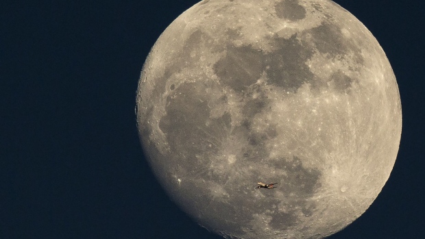 LONDON, ENGLAND - MARCH 03: A plane flies past the moon at sunset on March 3, 2015 in London, England. (Photo by Dan Kitwood/Getty Images)