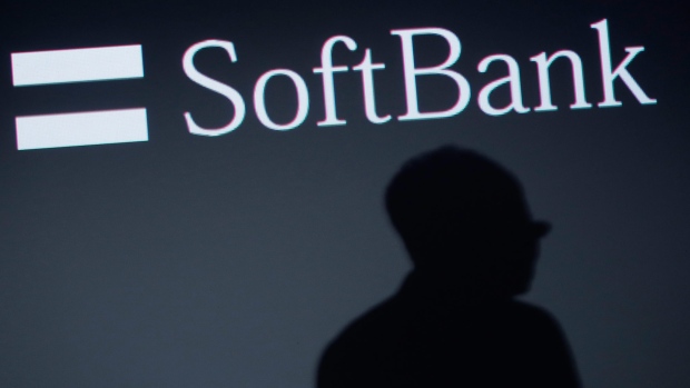 The shadow of Ken Miyauchi, executive vice president at SoftBank Corp. and chief executive officer of SoftBank's mobile unit, is cast against a screen displaying the company's logo. 