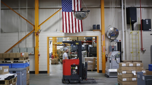 An American flag hangs above a worker operating a forklift at a manufacturing facility in Virginia Beach, Virginia. 