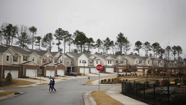 Pedestrians pass in front of residential buildings in the KB Home Glencroft neighborhood of Cary, North Carolina, U.S. 
